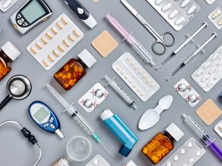 Directly above flat lay flat lay shot of various medical supplies. Full frame shot of medicines placed with syringes and diagnostic tools. All are on gray background.  Knolling concept.